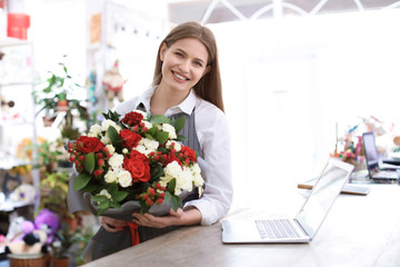 Female florist holding bouquet flowers at workplace