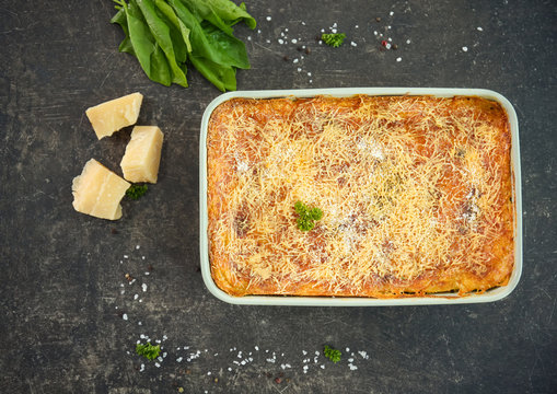 Baking dish of lasagna with spinach on grey background