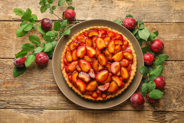 Delicious pie with plums on table