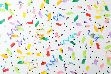 Colorful confetti and streamers on white background, top view