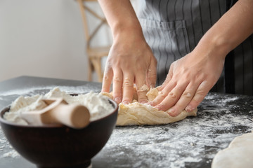 Woman kneading dough on table, closeup