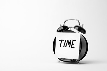 Alarm clock and sticky note with word TIME on white background