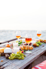 Picnic on beach at sunset in boho style. Romantic dinner, friends party, summertime, food and drink concept