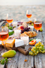 Picnic on beach at sunset in boho style. Romantic dinner, friends party, summertime, food and drink concept