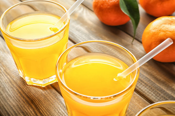 Glasses of tasty citrus juice on wooden table