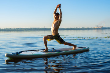 Man practicing yoga on a SUP board during sunrise