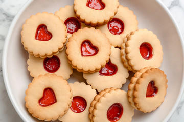 Traditional Christmas Linzer cookies with sweet jam on plate, top view