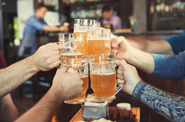 Friends clinking glasses with beer in pub