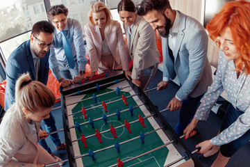 Smiling business colleagues playing table football