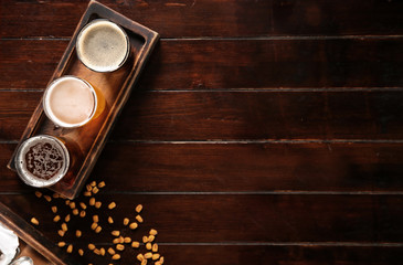 Glasses of tasty beer and snacks on wooden table