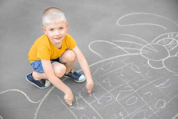 Naklejka premium Little child drawing bunny with colorful chalk on asphalt