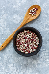 Motley beans in an old bowl and a wooden spoon.