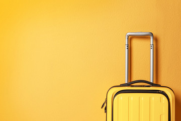 Bright yellow suitcase on color background