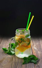 Detox water with lemon and mint. Summer drink in glass jar on rustic wooden background. Diet, healthy eating, weight loss concept.