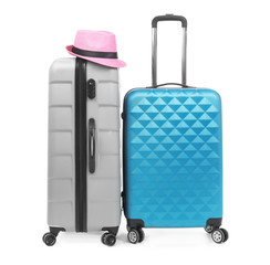 New suitcases and hat packed for journey on white background