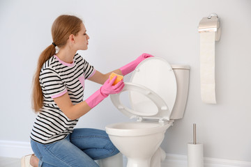 Woman cleaning toilet bowl in bathroom