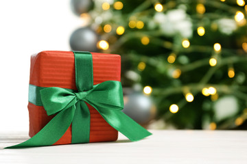 Beautiful gift box and blurred Christmas tree on background