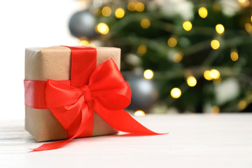Beautiful gift box and blurred Christmas tree on background