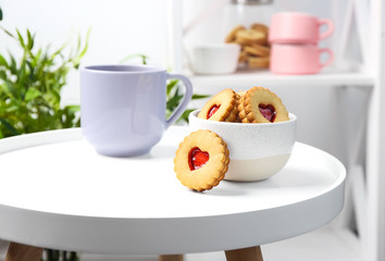 Traditional Christmas Linzer cookies with sweet jam and bowl on table