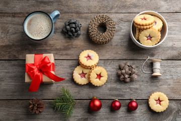 Traditional Linzer cookies with sweet jam and Christmas decorations on wooden background, top view