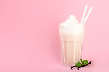 Glass with vanilla milk shake on color background