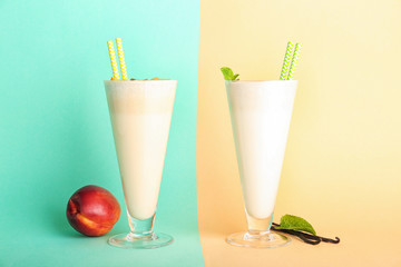 Glasses with delicious milk shakes on color background