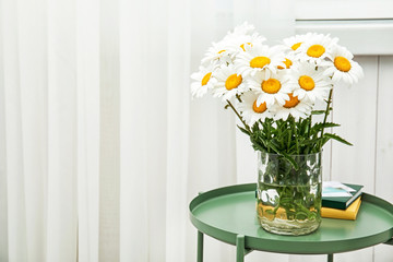 Vase with beautiful chamomile flowers on table
