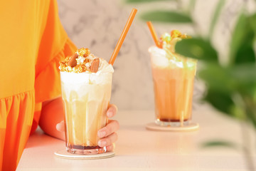 Woman with glass of delicious milk shake at table indoors