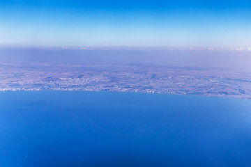 Airplane view over Cyprus, relief of the island and beautiful turquoise Mediterranean with boats and ships in the waters. Airplane wings in the early morning.