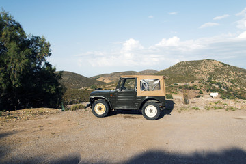 Fototapeta na wymiar A vintage suv land vehicle in the beautiful scenic landscape of the island Patmos, Greece in summer