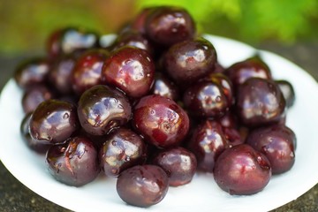 Pile of dark red cherryon white plate.
