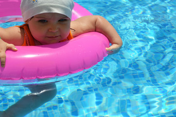 Portrait of happy white Caucasian child baby girl toddler in swimming pool outdoor. Preschool boy training to float with pink inflatable circle ring in water. Healthy active lifestyle. summer, joy