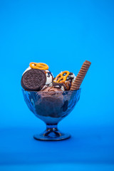 Ice cream in glass bowls with with biscuits and topping. Summer and sweet menu concept flat lay. Isolated on blue background