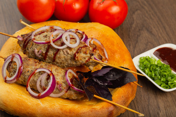 Lulya-kebab. Shish kebab on a stick, minced meat. Traditional Caucasian dish. On a cutting board, with green salad, ketchup, spices