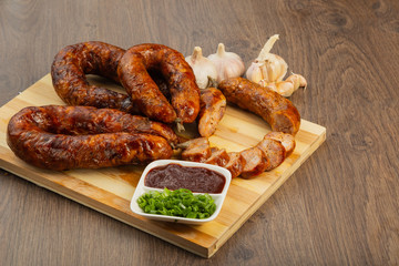 Homemade sausage on a wooden background with seasonings and sauce.