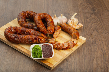 Homemade sausage on a wooden background with seasonings and sauce.