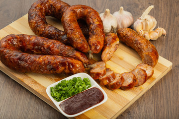Homemade sausage on a wooden background with seasonings and sauce.