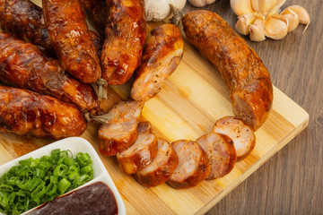 Homemade sausage on a wooden background with seasonings and sauce.