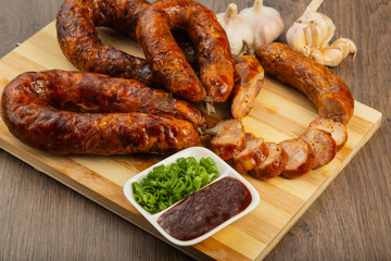 Homemade sausage on a wooden background with seasonings and sauce.