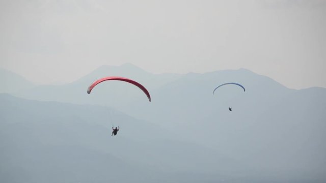 Paragliding. A tourist paragliding over a hills. Flying paragliders in the mountains. Parachute In The Sky. Extreme sport and adventure