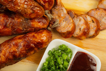 Homemade sausage on a wooden background with seasonings and sauce.