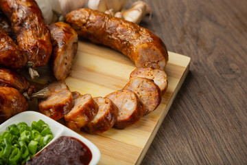 Homemade sausage on a wooden background with seasonings and sauce.