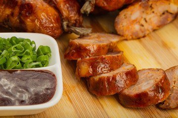 Homemade sausage on a wooden background with seasonings and sauce.