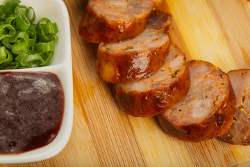 Homemade sausage on a wooden background with seasonings and sauce.