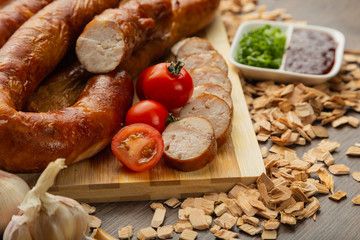 Homemade sausage on a wooden background with seasonings and sauce.