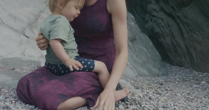 Mother sitting on beach with little toddler