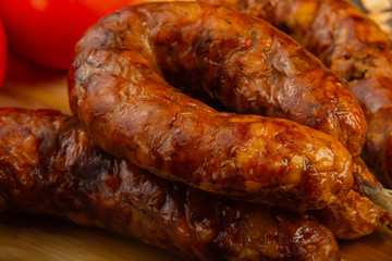 Homemade sausage on a wooden background with seasonings and sauce.