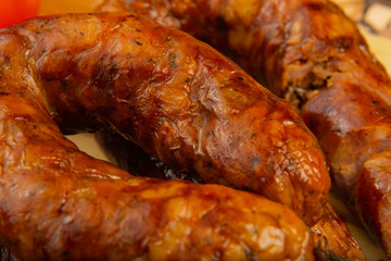 Homemade sausage on a wooden background with seasonings and sauce.