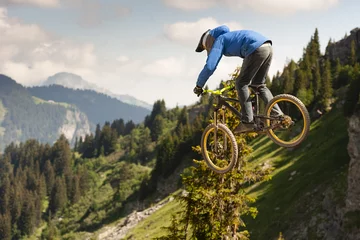 Tableaux ronds sur aluminium Vélo Mountain biker jumps on the background of a beautiful mountain view