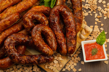 Homemade sausage on a wooden background with seasonings and sauce.